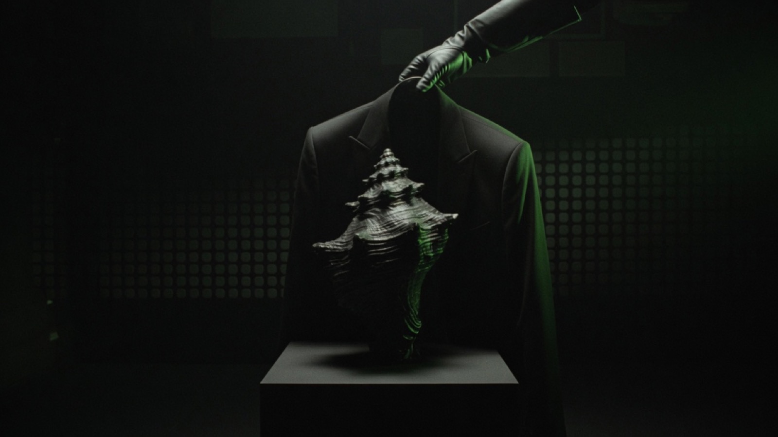 A gloved hand holds the collar of a black jacket behind a large dark conch shell on a pedestal.